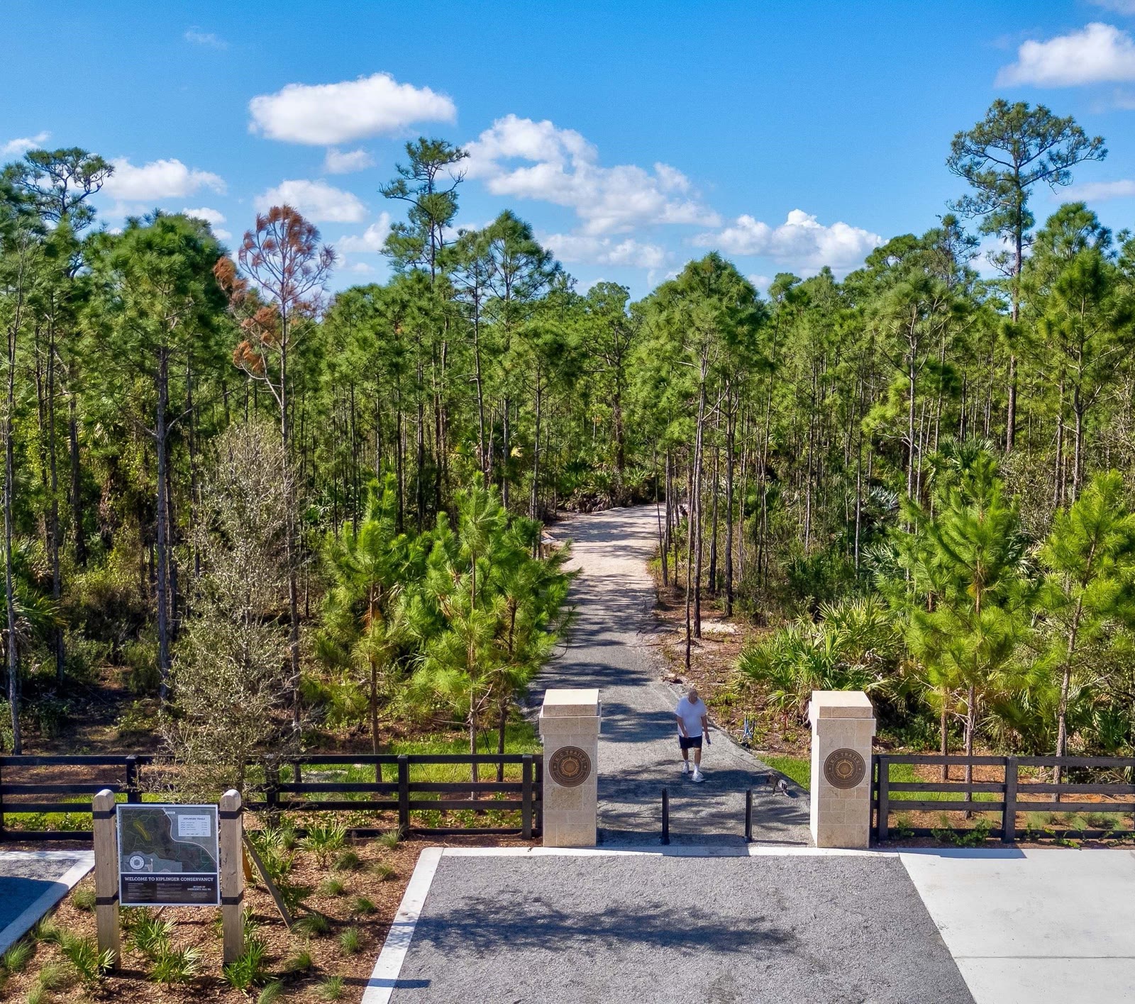 Kiplinger Conservancy trailhead entrance with stone pillars and a gravel trail into the pines